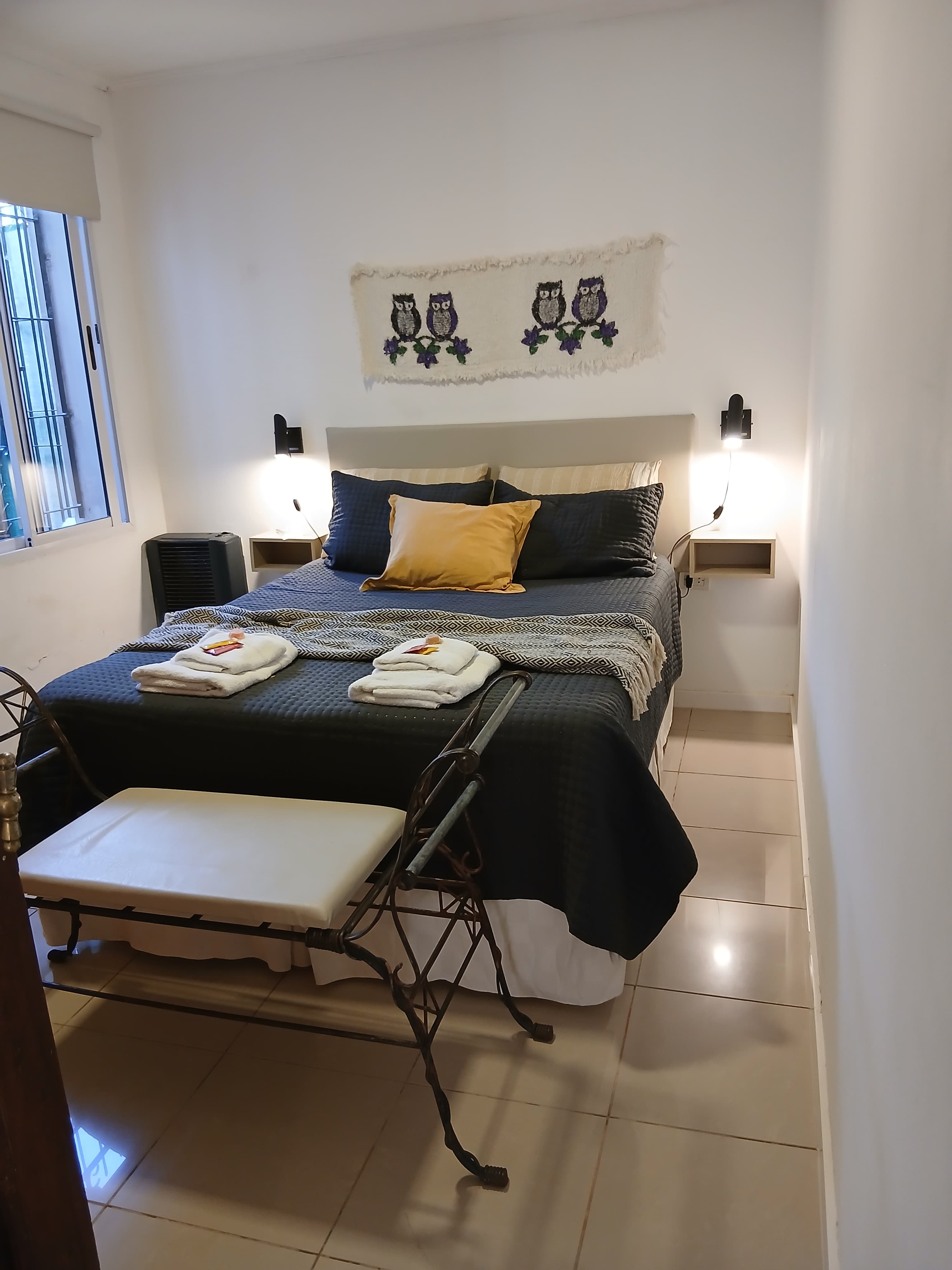 Dormitorio con cama de dos plazas, mesas de luz y calefactor