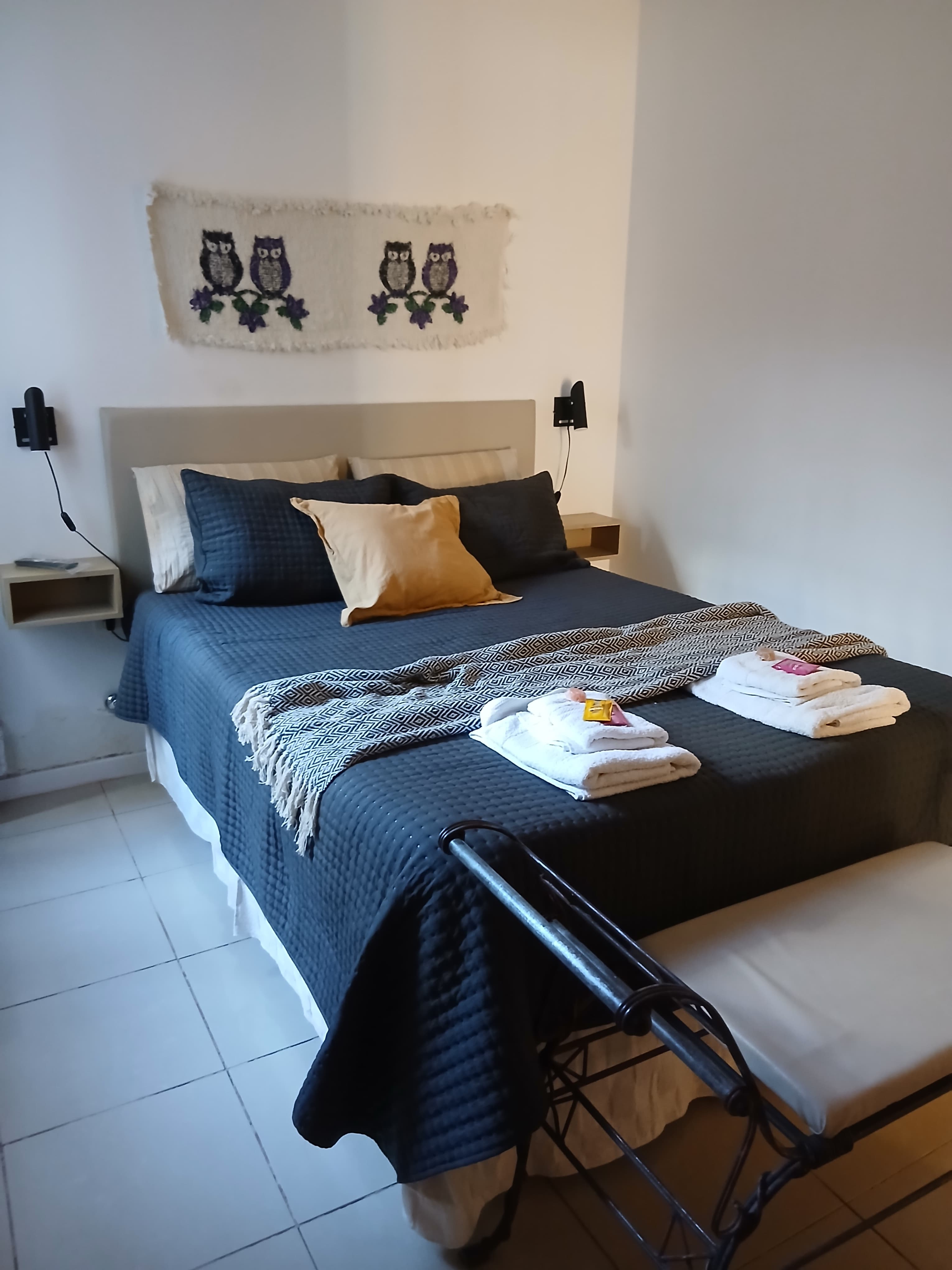 Dormitorio con cama vestida, toallas y detalles de bienvenida